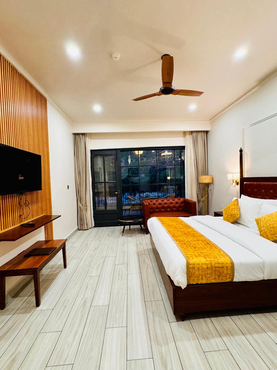 Luxury Room at night at Tiraya — king bed, leather sofa, wood panel TV wall, balcony view